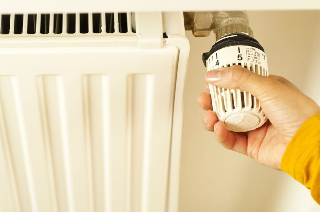 Main réglant le robinet thermostatique d'un radiateur
