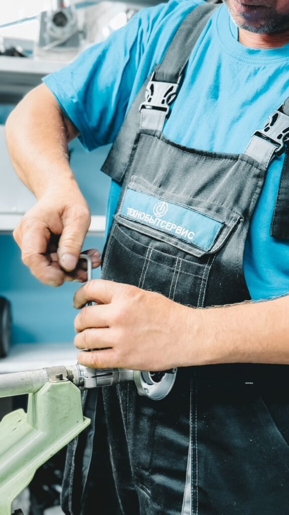 Plombier en uniforme réparant une canalisation avec une clé